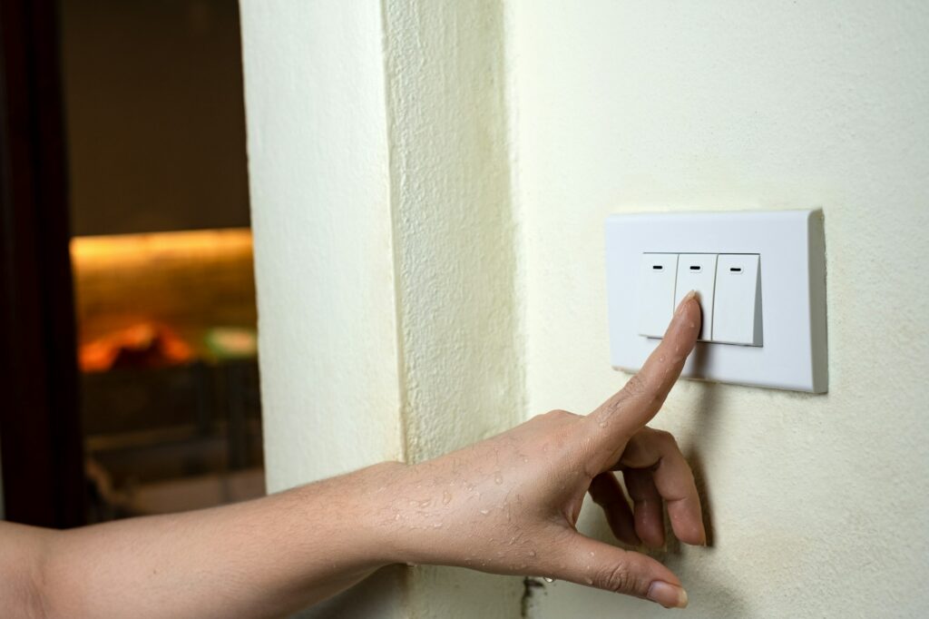 Wet hand turn on lights electric switch on white wall background