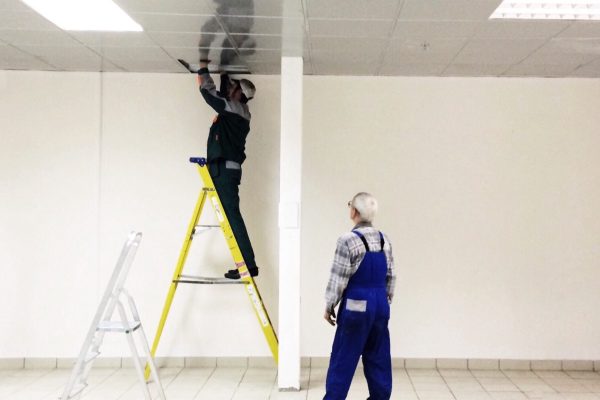 Electricians repair lighting in the trade building