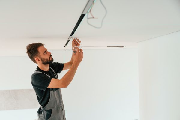 Installing lighting equipment on the ceiling. Man is working indoors at domestic room