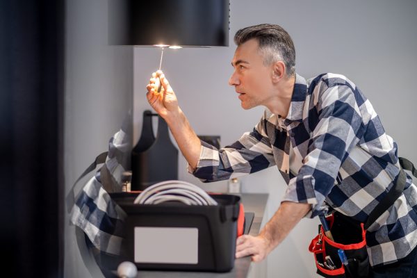 Profile of man touching lamp on kitchen hood